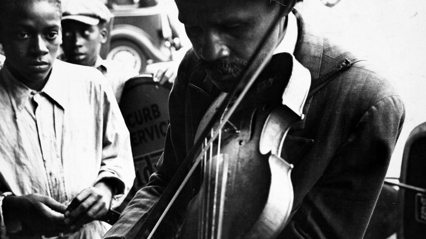 Un musicien aveugle jouant du violon et deux garçons en arrière-plan, West Memphis, Arkansas, 1935 ; photographie de Walker Evans.