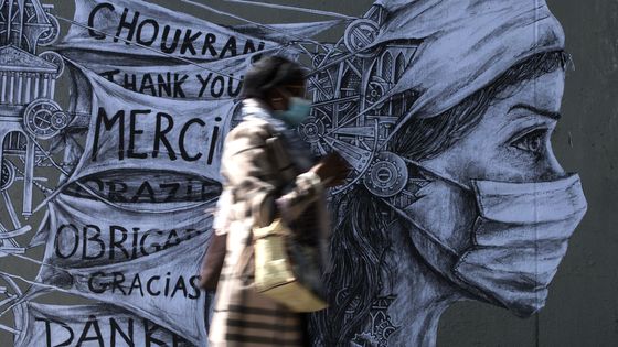 Une femme portant un masque devant une œuvre du street artiste Ardif à Paris, 15/05/2020. ©AFP - OEL SAGET / AFP