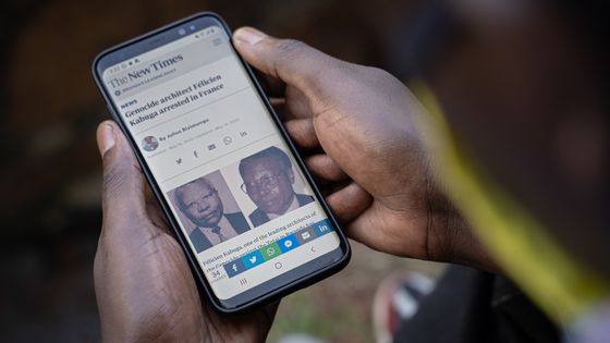 Un homme regarde sur son smartphone, à Kigali, au Rwanda, un article du « New York Times » relatant l’arrestation de Félicien Kabuga le 16 mai 2020 près de Paris. Photo prise le 18 mai 2020. ©AFP - SIMON WOHLFAHRT