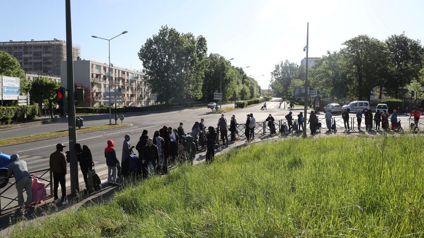 Des habitants de Clichy-sous-Bois font la queue en attendant de recevoir de l'aide alimentaire auprès de l'association ACLEFEU, le 22 avril 2020. À ce moment, la France entame son 37e jour de confinement.