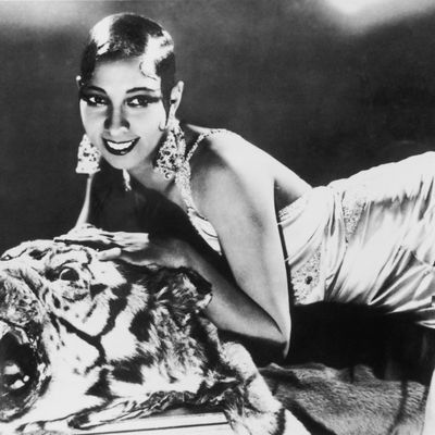 Portrait of American-born singer and dancer Josephine Baker (1906 - 1975) lying on a tiger rug in a silk evening gown and diamond earrings.