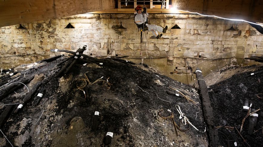 Déblaiement des débris de la charpente présents sur l’extrados des voûtes hautes de la cathédrale par un cordiste (dans le chœur).