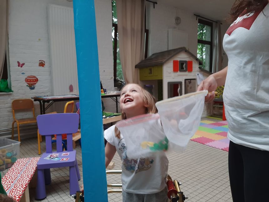 Aurore attrape des papillons en papier et en même temps la petite fille apprend à lacher une main en étant debout.