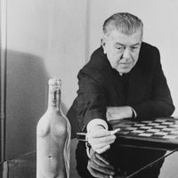 René Magritte (1898 - 1967) avec sa 'Femme-Bouteille', peinture de femme nue sur une bouteille en verre, en 1955 environ.