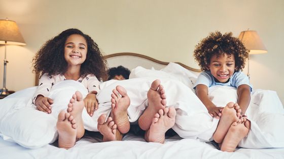 Deux enfants s'amusant dans le lit de leurs parents ©Getty - PeopleImages