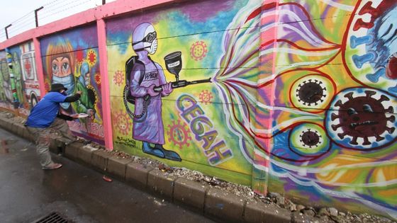 Un street-artiste indonésien réalise une peinture murale en pleine crise du Covid-19 à Tangerang, Indonésie, le 19 janvier 2021. ©AFP - Demy SANJAYA