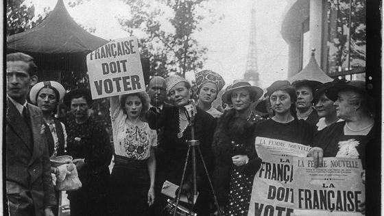 Lors de l'Exposition internationale des arts et techniques à Paris en 1937 : une manifestation pour le droit de vote des femmes françaises. Louise Weiss est derrière le micro. - Photographie de presse sur Gallica, BNF, domaine public