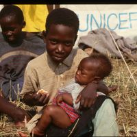 Un orphelin rwandais allaite un bébé dans un orphelinat de l'Unicef, Katale Camp, Zaïre.