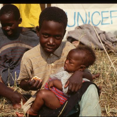 Un orphelin rwandais allaite un bébé dans un orphelinat de l'Unicef, Katale Camp, Zaïre.