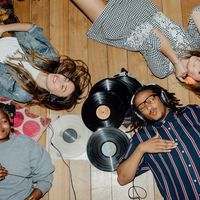 Quatre jeunes gens, casques sur les oreilles, écoutent de la musique allongés au sol.