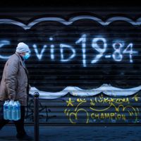 Le 10 décembre 2020 à Paris, un homme masqué marche devant une inscription "Covid 1984" inscrite en référence aux mesures de confinement prévues par l'état d'urgence sanitaire.