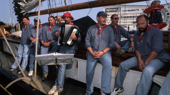 Groupe de chanteurs sur le pont d'un bateau lors de la Fête des chants de marins à Paimpol en 1997, Bretagne, France. ©Getty - Gérald MORAND-GRAHAME/Gamma-Rapho