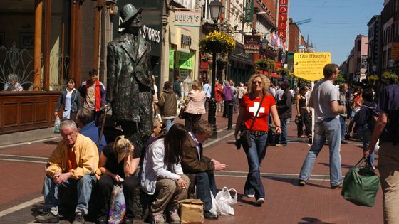En 2004, des touristes sont assis au pied de la statue de l'écrivain irlandais James Joyce, auteur de "Ulysse" et "Finnegans Wake" qui ont pour cadre Dublin. ©AFP - Fran CAFFREY / NEWSFILE