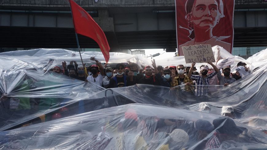 A Rangoun, les manifestants se protègent avec une bâche de plastique contre les canons à eau de la police