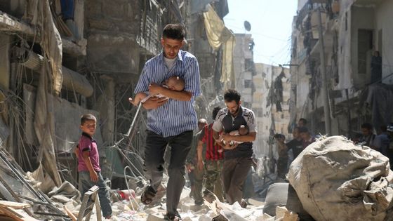 Photo prise le 9 juin 2016, qui montre des casques blancs et des habitants évacuant des résidents dont l'immeuble à Alep a été touché par une attaque aux barils d'explosifs ©AFP - AMEER AL-HALBI