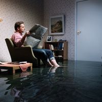 Un homme lit le journal pendant que son salon est inondé