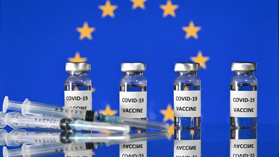 Flacons de vaccin anti-Covid sur fond de drapeau européen ©AFP - JUSTIN TALLIS