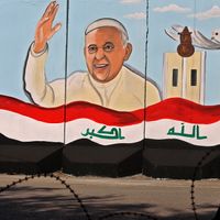 Une femme irakienne passe devant une peinture murale représentant le pape François sur les murs extérieurs de l'église Notre-Dame du Salut (Sayidat al-Najat), à Bagdad, le 22 février 2021.