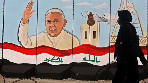 Une femme irakienne passe devant une peinture murale représentant le pape François sur les murs extérieurs de l'église Notre-Dame du Salut (Sayidat al-Najat), à Bagdad, le 22 février 2021. ©AFP - AHMAD AL-RUBAYE