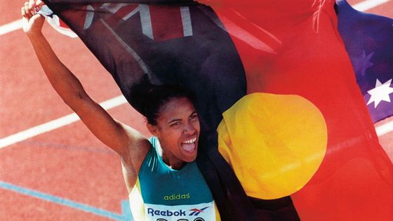 Cathy Freeman, athlète australienne spécialiste du 400 mètres, championne olympique et double championne du monde de la discipline célèbre sa victoire et son héritage culturel en agitant les drapeaux australiens et aborigènes en 2006. ©Getty - The AGE / Fairfax Media