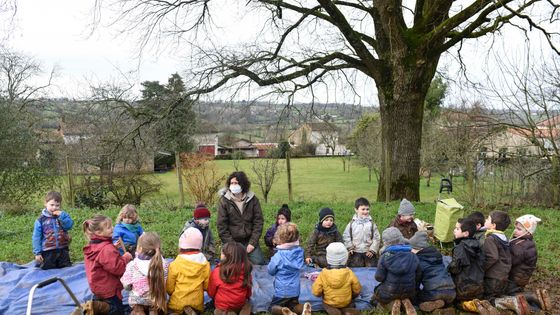 Elèves assis dans un champ avec leur institutrice pour une leçon en contact avec la nature à Clavé en France, le 4 février 2021. ©AFP - SEBASTIEN SALOM-GOMIS