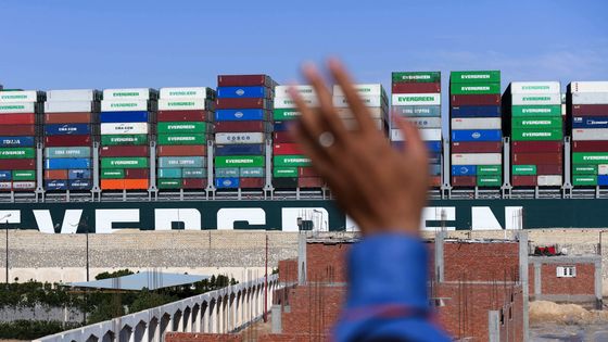 Un homme salue le porte-conteneurs «Ever Given» alors qu'il est remorqué au canal de Suez en Égypte après avoir été complètement délogé des rives, le 29 mars 2021. ©AFP - Ahmad HASSAN