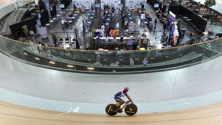 Un membre de l'équipe de France de cyclisme sur piste s'entraîne pendant que des personnes se font vacciner au Vélodrome de Saint-Quentin-en-Yvelines..