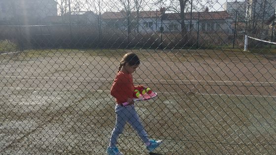 Une petite fille derrière une grillage sur un terrain de tennis ©Radio France - Natacha Kadur