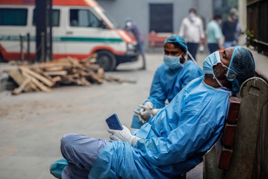 Les employés du cimetière aidant les gens à incinérer les corps de leurs proches décédés du Covid-19 font une pause dans un crématorium, à New Delhi.