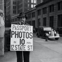 Homme sandwich proposant de réaliser rapidement des photos pour passeport. 4/13/1934.