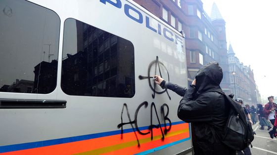 Un manifestant repeint un fourgon de police à Londres, le 26 mars 2011. ©AFP - CARL COURT