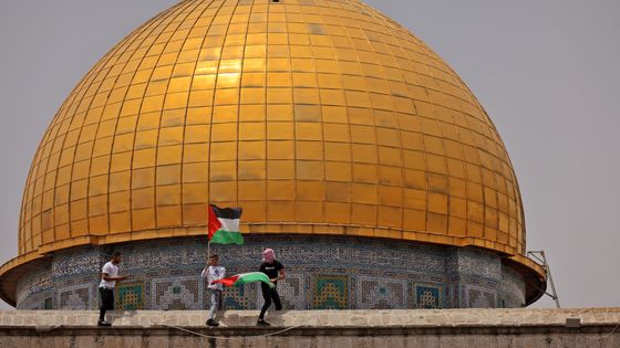 Des fidèles musulmans palestiniens brandissent leur drapeau national lors d'affrontements avec les forces de sécurité israéliennes dans l'enceinte de la mosquée Al-Aqsa à Jérusalem, le 21 mai 2021. ©AFP - AHMAD GHARABLI