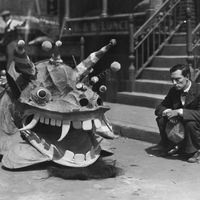 Stony-faced American comedian Buster Keaton (1895 - 1966) watches a Chinese dragon pass by, in a scene from the film 'The Cameraman', directed by Edward Sedgwick and Keaton for MGM.(Photo by Hulton Archive/Getty Images)