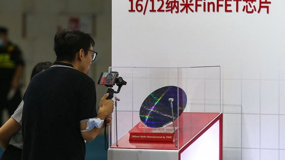 Un visiteur prend des photos d'une puce de Taiwan Semiconductor Manufacturing Company (TSMC) lors de la Conférence mondiale sur les semi-conducteurs 2020 à Nanjing, en Chine, le 26 août 2020. ©AFP - STR