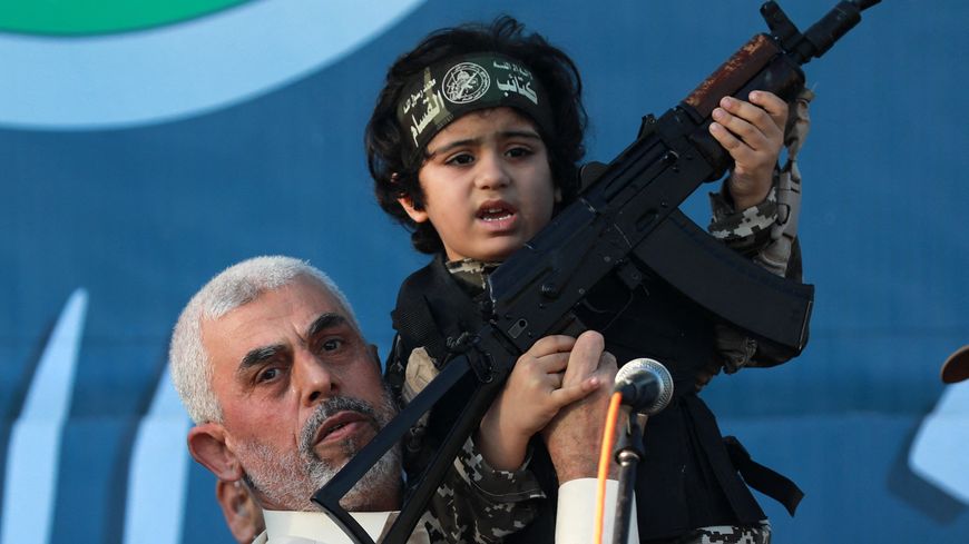 Yahya Sinouar, qui a pris la tête du Hamas début 2017, tient un enfant en costume de soldat sur scène avec une arme pour les caméras, lors d'un rassemblement de partisans le 24 mai 2021 à Gaza.