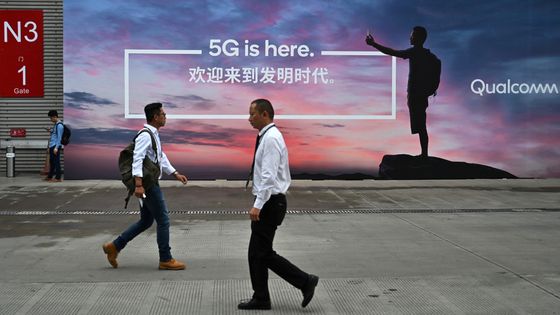 Des passants devant une affiche publicitaire pour l'internet 5G lors du Mobile World Congress afin de présenter la technologie au Shanghai New International Expo Centre à Shanghai, le 26 juin 2019. ©AFP - HECTOR RETAMAL