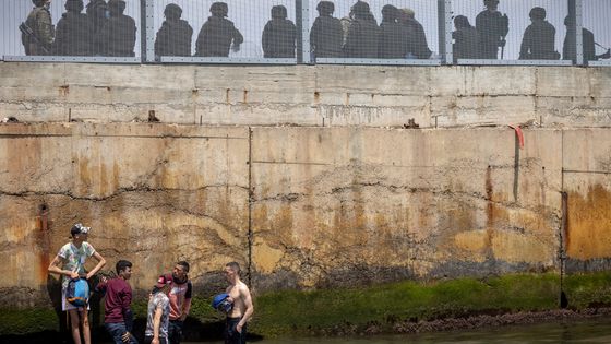 Des soldats et des policiers espagnols montent la garde auprès des migrants qui ont tenté de traverser la frontière entre le Maroc et l'enclave espagnole de Ceuta le 18 mai 2021 à Fnideq ©AFP - FADEL SENNA