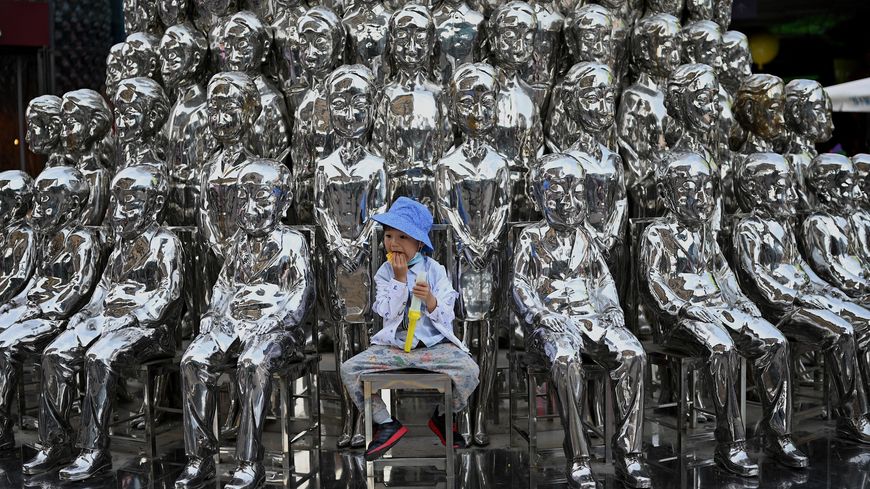 Un jeune garçon assis parmi des sculptures dans un centre commercial de Pékin le 1er juin 2021, jour international de l'enfant, au lendemain de l'annonce par la Chine qu'elle autorisait les couples à avoir 3 enfants
