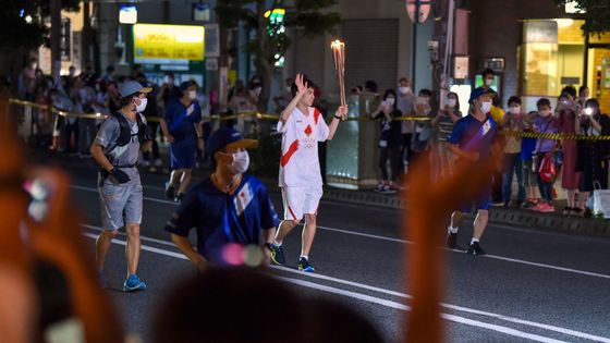 Un sportif court avec la torche olympique lors du relais de la flamme des Jeux Olympiques de Tokyo à Numazu, préfecture de Shizuoka, le 24 juin 2021 ©AFP - Kazuhiro NOGI