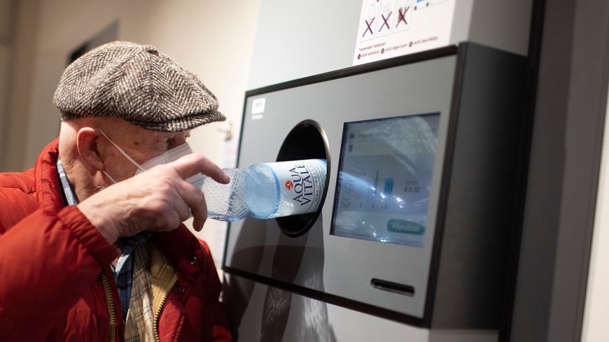Bouteille plastique - un homme dépose une bouteille dans une machine à recycler (Ute Grabowsky)