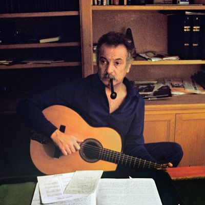 Georges Brassens, chanteur et compositeur français, joue de la guitare chez lui en fumant la pipe avant sa rentrée dans un music-hall parisien en octobre 1972.