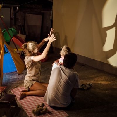 Des parents et leurs enfants jouent aux ombres projetées sur le mur de leur maison