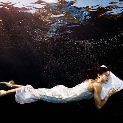 Femme, la tête posée sur un oreiller, dormant sous l'eau