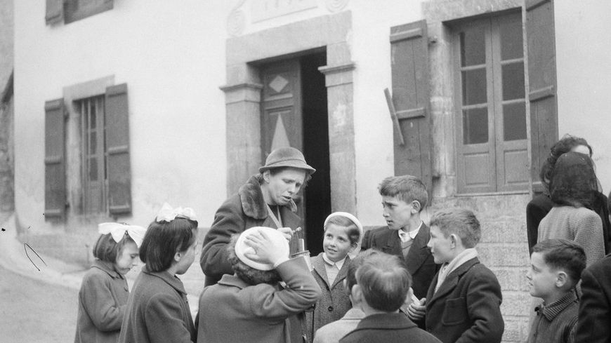 Claudie Marcel-Dubois s'informe sur le fonctionnement du toulouhou auprès d'enfants lors d'une mission d'ethnomusicologie dans les Pyrénées centrales (mars-avril 1956)