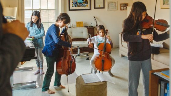 Enfants jouant des instruments à cordes sous l'oeil de leur père ©Getty - Cavan Images