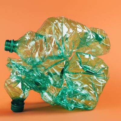 Amas de bouteilles vertes en plastique, sur fond orange