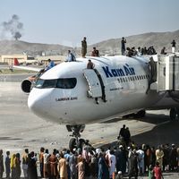 Afghans montant sur le toit d'un avion à l'aéroport de Kaboul le 16 Août 2021