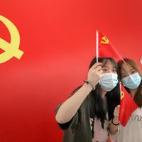 Des passagères posent avec un drapeau du Parti communiste chinois à l'occasion de son centième anniversaire à la gare de Nantong en Chine le 1er juillet 2021.