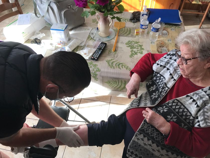 Alexandre, infirmier libéral, change le pansement d'ulcère d'une de ses patientes.