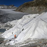 Un homme sur le glacier du Rhône en Suisse partiellement recouvert de mousse isolante pour l'empêcher de fondre en raison du réchauffement climatique près de Gletsch, le 27 octobre 2021.